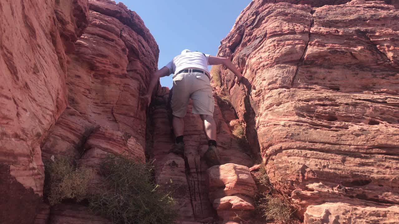 Escursionista che si arrampica su una roccia nell'area di conservazione nazionale di Red Rock Canyon in Nevada.
