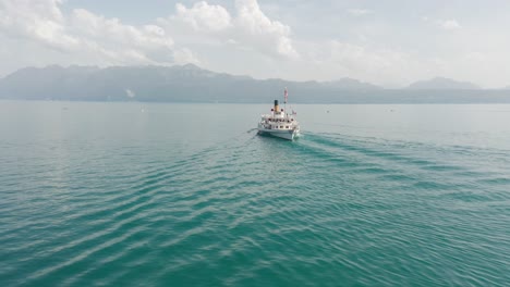 wide aerial orbit of a beautiful old cruise ship on lake geneva with the city of lausanne in the background