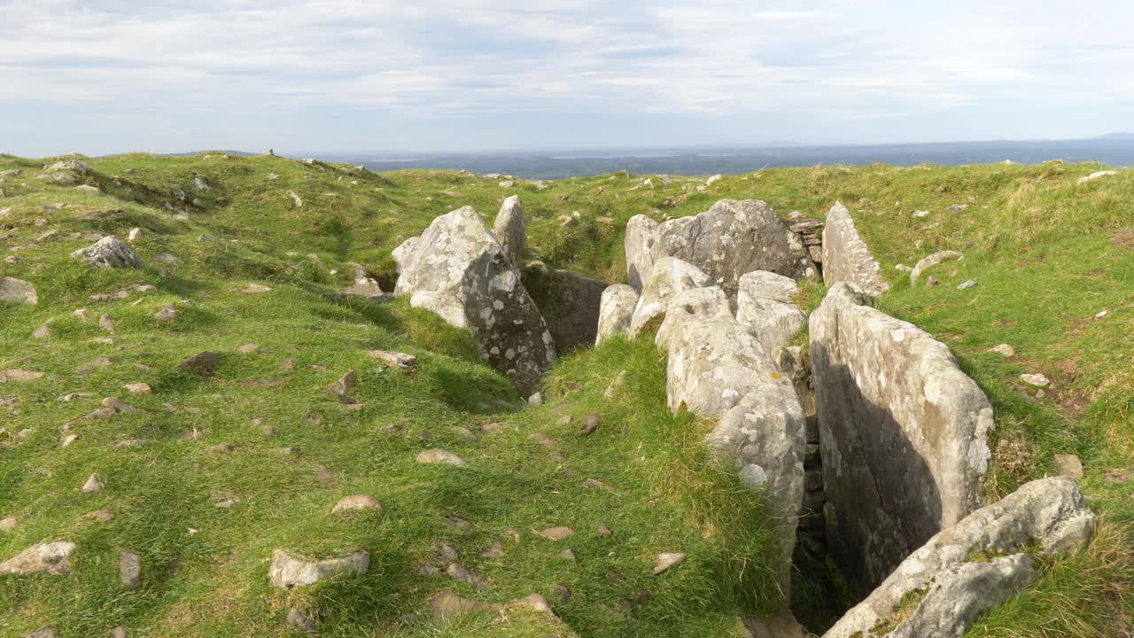 Camera in pietra in rovina di una tomba a corridoio con vista sulle pianure irlandesi