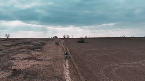 Luftbild-Von-Mann-Und-Kindern,-Die-Auf-Der-Landstraße-Zwischen-Den-Feldern-Fahrrad-Fahren