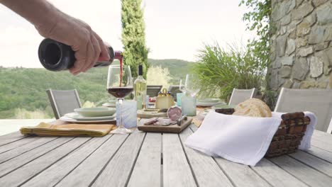 Camarero-Mano-Masculina-Vertiendo-Vino-Tinto-Italiano-En-Un-Vaso-Sobre-Una-Mesa-Con-Pan-Y-Aperitivo-Comida-Gourmet