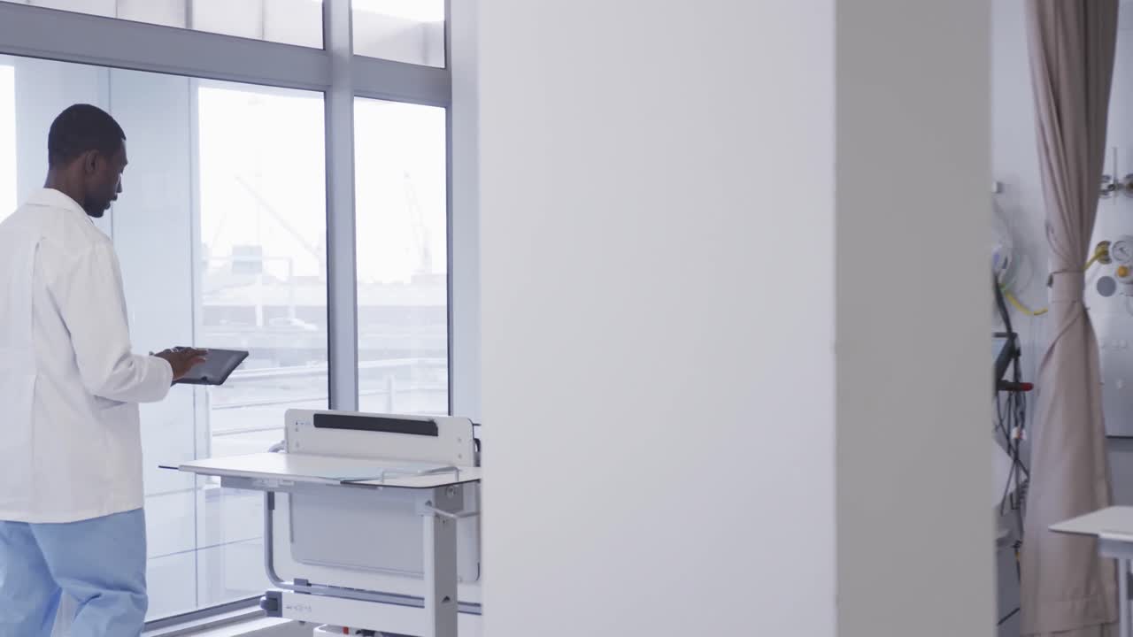 African american male doctor using tablet in hospital room, slow motion