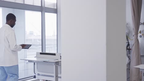 afrikanisch-amerikanischer männlicher arzt mit tablet im krankenhauszimmer, zeitlupe