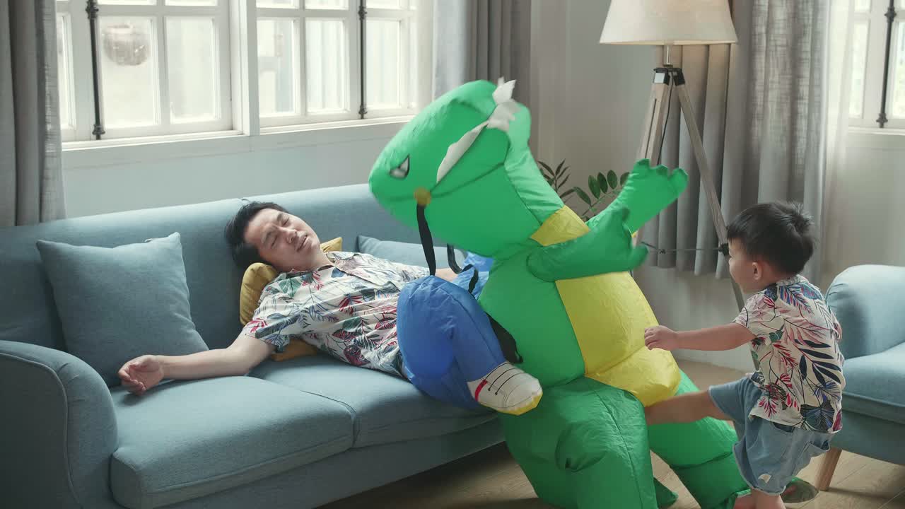 Tried Asian Father After Play With His Son,  Funny Boy Kick Dinosaur Toy In Modern House Living Room, Happy Family Father With Child Boy Having Fun Enjoy Playing Funny Activity Together At Home