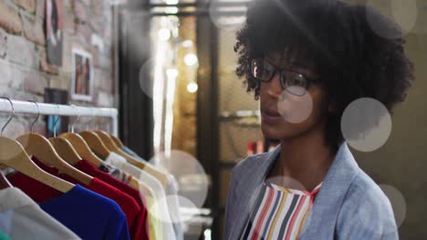 animation of light spots over african american woman in clothes shop