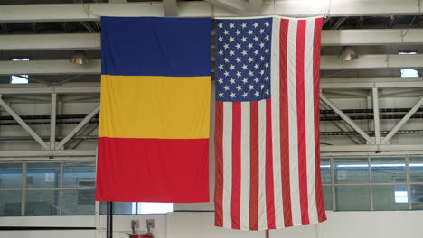 bandera de estados unidos y rumania colgando una al lado de la otra en el edificio del hangar