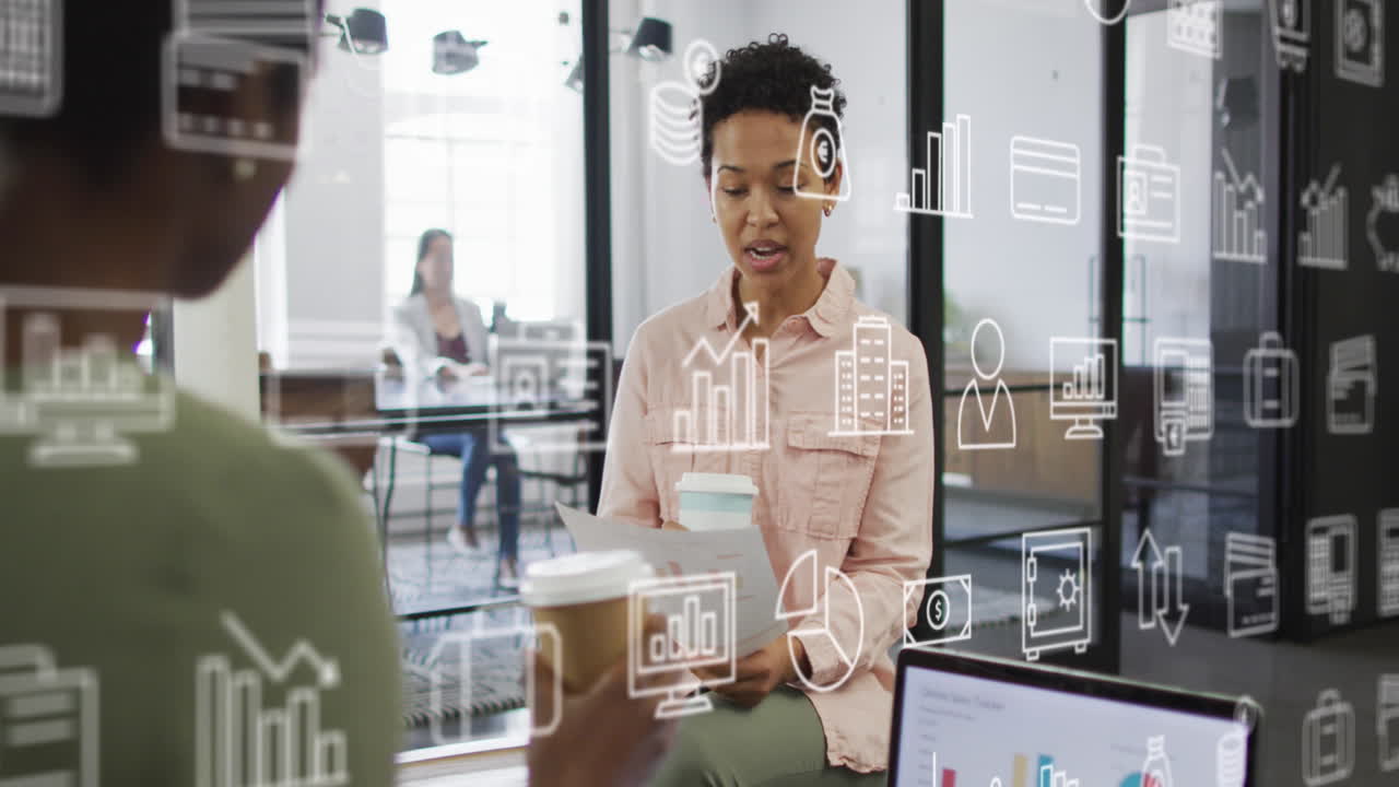 Animation of business icons over diverse businesswomen discussing work