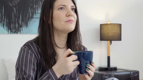 Close-up-of-young-woman-sitting-on-the-bed-in-the-morning-and-drinking-coffee