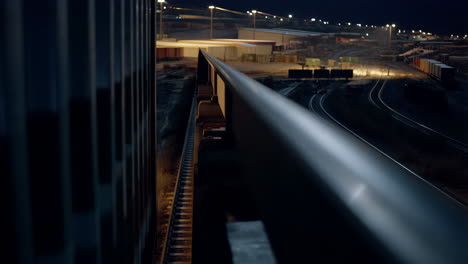 night view of a train yard with blurred lights and a metal railing