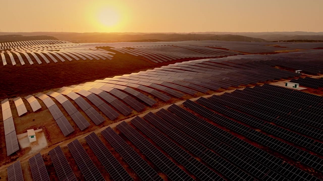 Luftfoto af stor solcellepark ved solnedgang