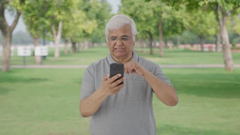 Un-Anciano-Indio-Somnoliento-Desplazándose-Por-El-Teléfono-En-El-Parque