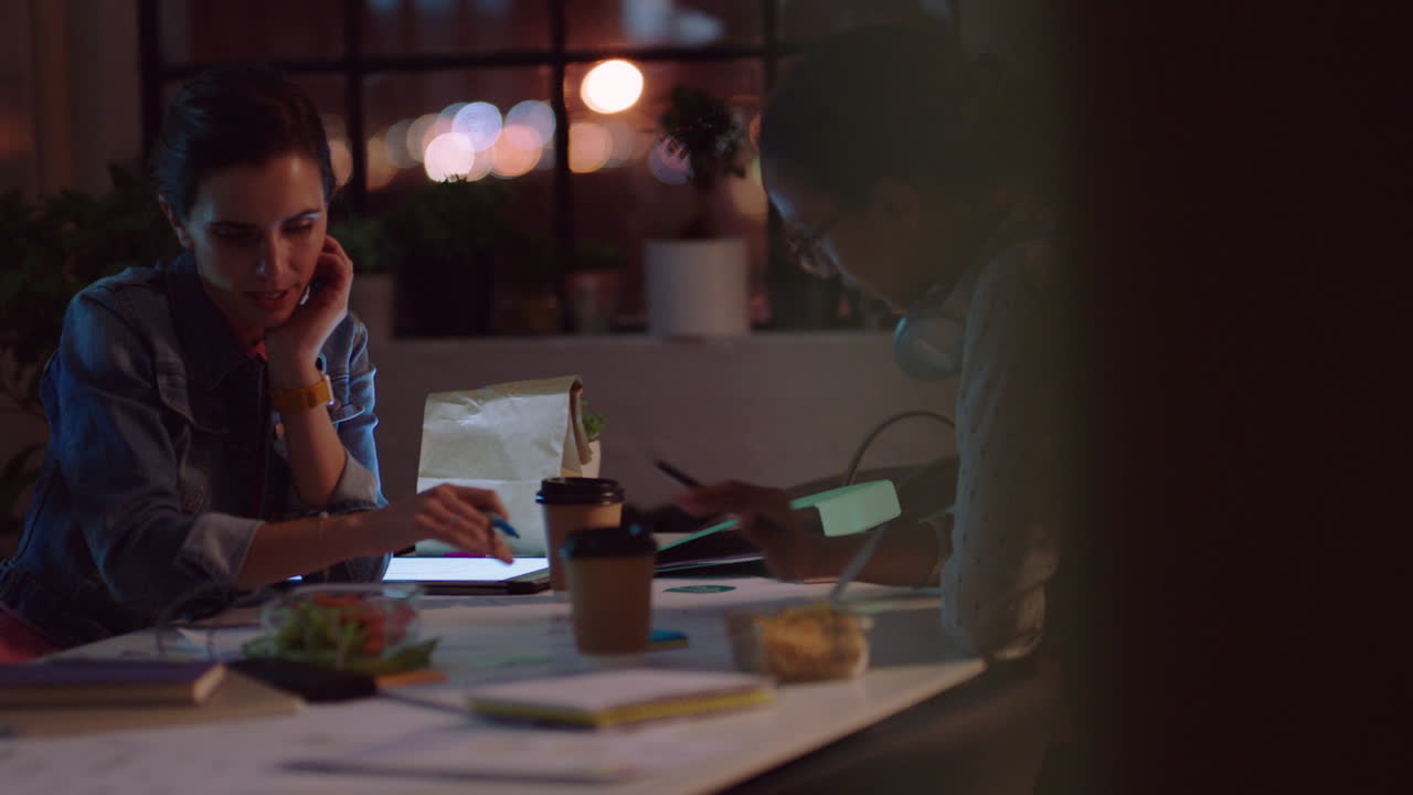 business people working late marketing team designing company logo female entrepreneurs brainstorming ideas planning creative project deadline in office at night
