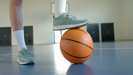 balancing foot on basketball, athlete preparing for game in indoor court