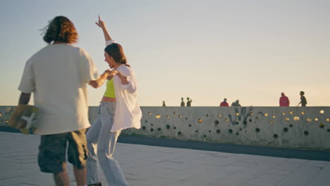 teen pair riding skate board enjoying sunset stadium. woman balancing skateboard