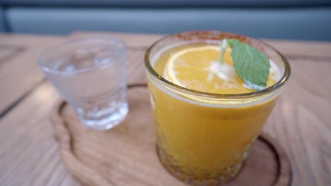 closeup of a glass of orange juice with a mint leaf and an orange slice on top