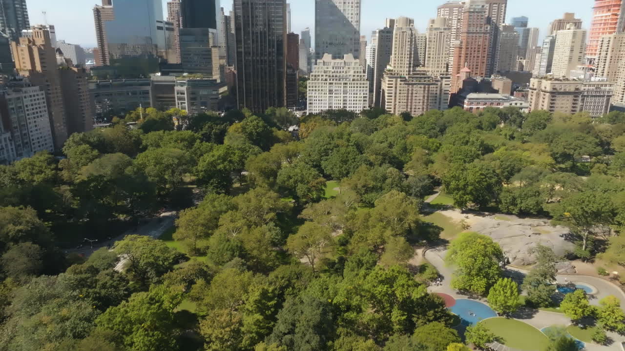 Plano aéreo inclinado hacia atrás sobre Central Park, día soleado en la ciudad de Nueva York