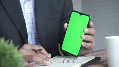 businessman holding a smartphone with a green screen