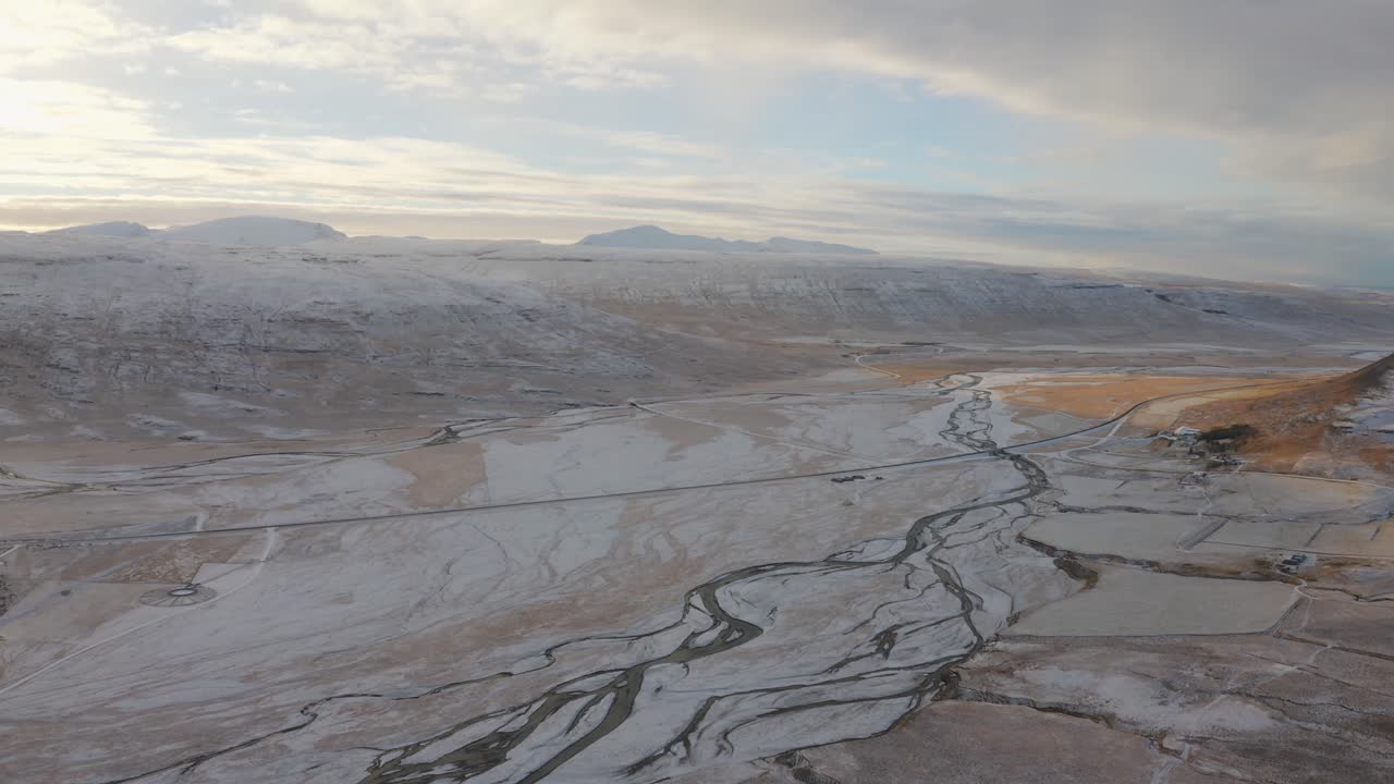 drone vuela sobre impresionantes ríos que atraviesan el desinhibido y helado valle de los fiordos del oeste con ríos congelados durante el frío invierno, antena en islandia, país de las maravillas del invierno nevado