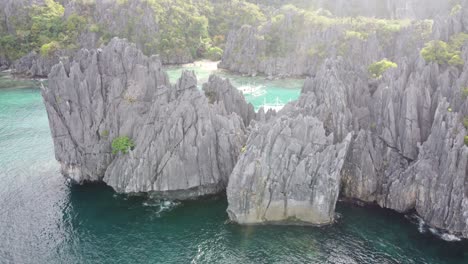 Island-hopping-boats-anchored-in-small-Lagoon---El-Nido-amid-jagged-karst-and-rock-outcrops