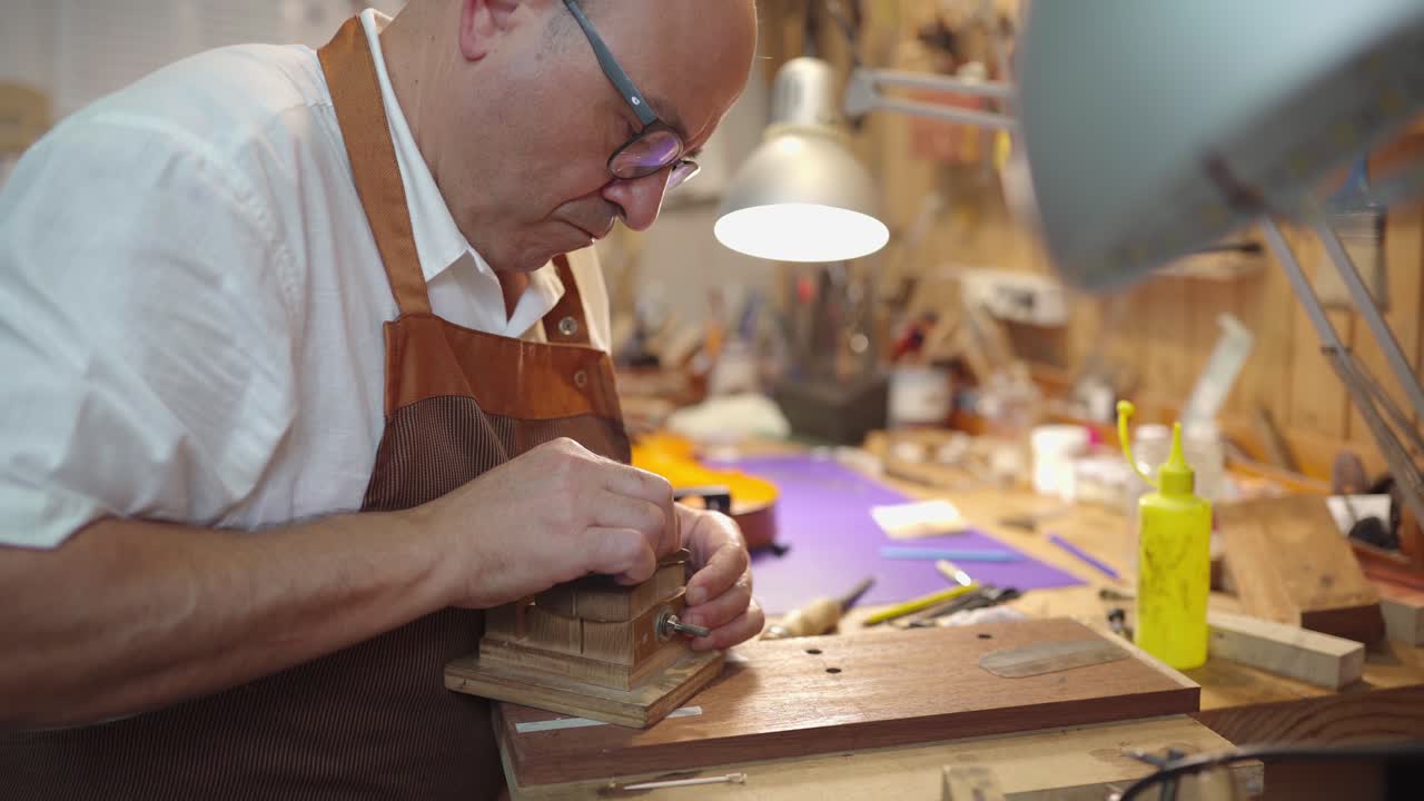 Luthier with violin bridge in workshop