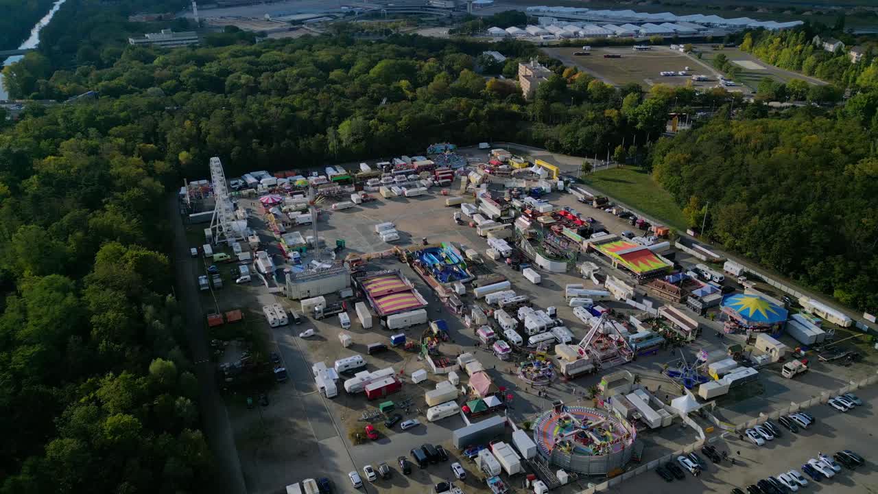 outdoor forest fairground, funfair, carnival with rides and stalls surrounded by forest. Perfect aerial view flight drone shot from above