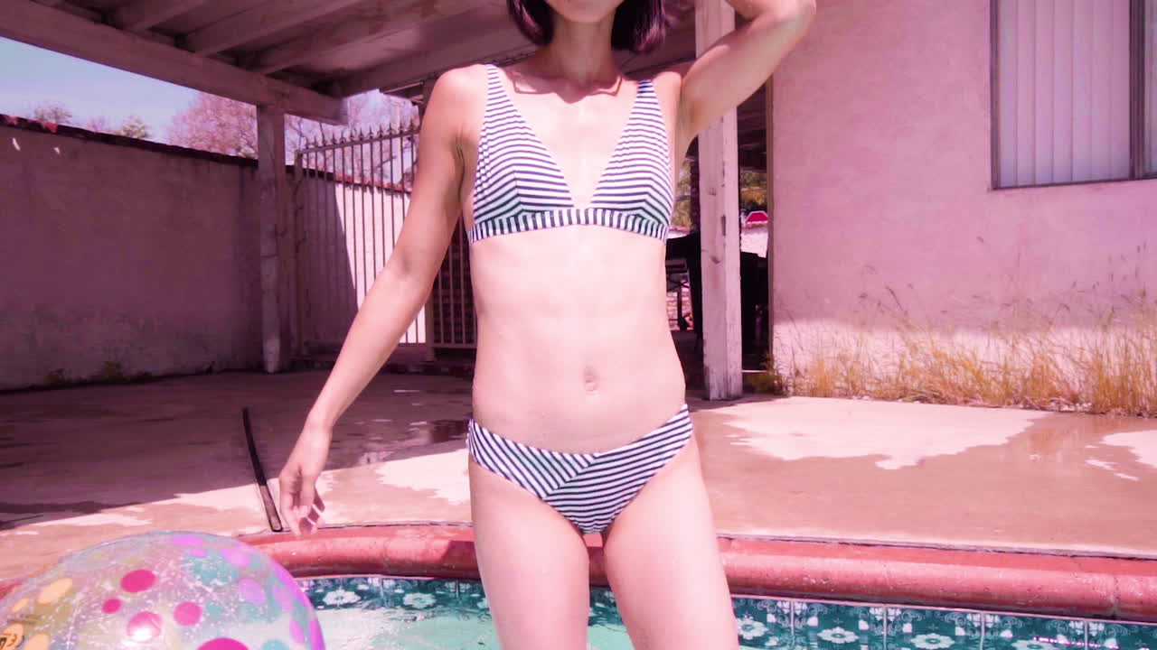 Female walking into the pool enjoying the sun