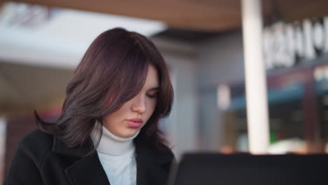 joven adulta sentada, centrada en su computadora portátil, absorta en el trabajo o el estudio, iluminación suave, fondo borroso crea una atmósfera de concentración y calma