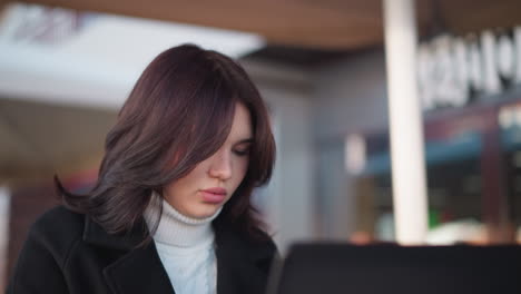 young adult woman seated, focused on her laptop, absorbed in work or study, soft lighting, blurred background creates an atmosphere of concentration and calm