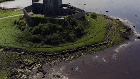 dunguaire castle: aerial tilt-up from sunlit water reflection to the castle