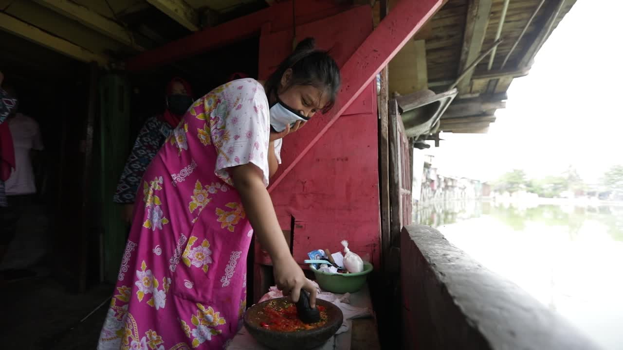the woman grinds the sambal Stone mortar and pestle with selfmade sambal at a local warung in Indonesia