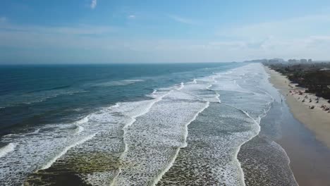 incredible establishing panorama shot of big waves and beach in itanhaem, brazil, great color of ocean and clouds