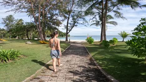 mujer italiana caminando hacia una playa tropical desde atrás