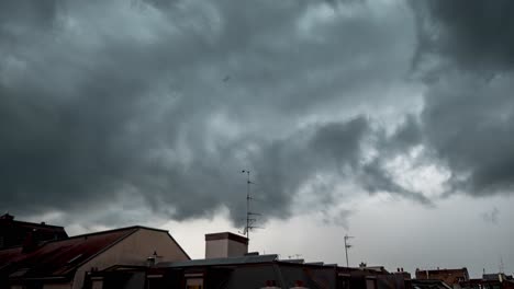 dark gray ominous sky and turbulent storm clouds approach and swirl from distance, time lapse