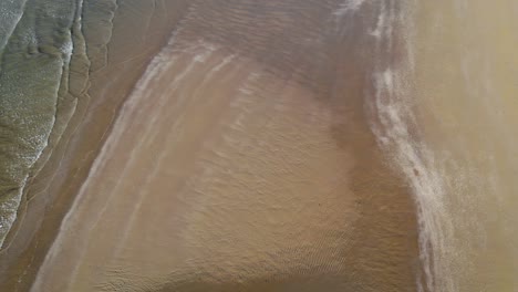 Aerial-revealing-the-breakwaters-and-waves-hitting-the-beach-of-Caorle,-an-Adriatic-town-of-Venice