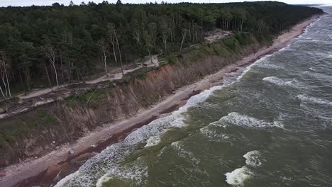 revelando un acantilado costero altísimo a lo largo del mar báltico en lituania, capturado por un dron, mostrando olas turbulentas y aguas verdes vibrantes con tonos atmosféricos