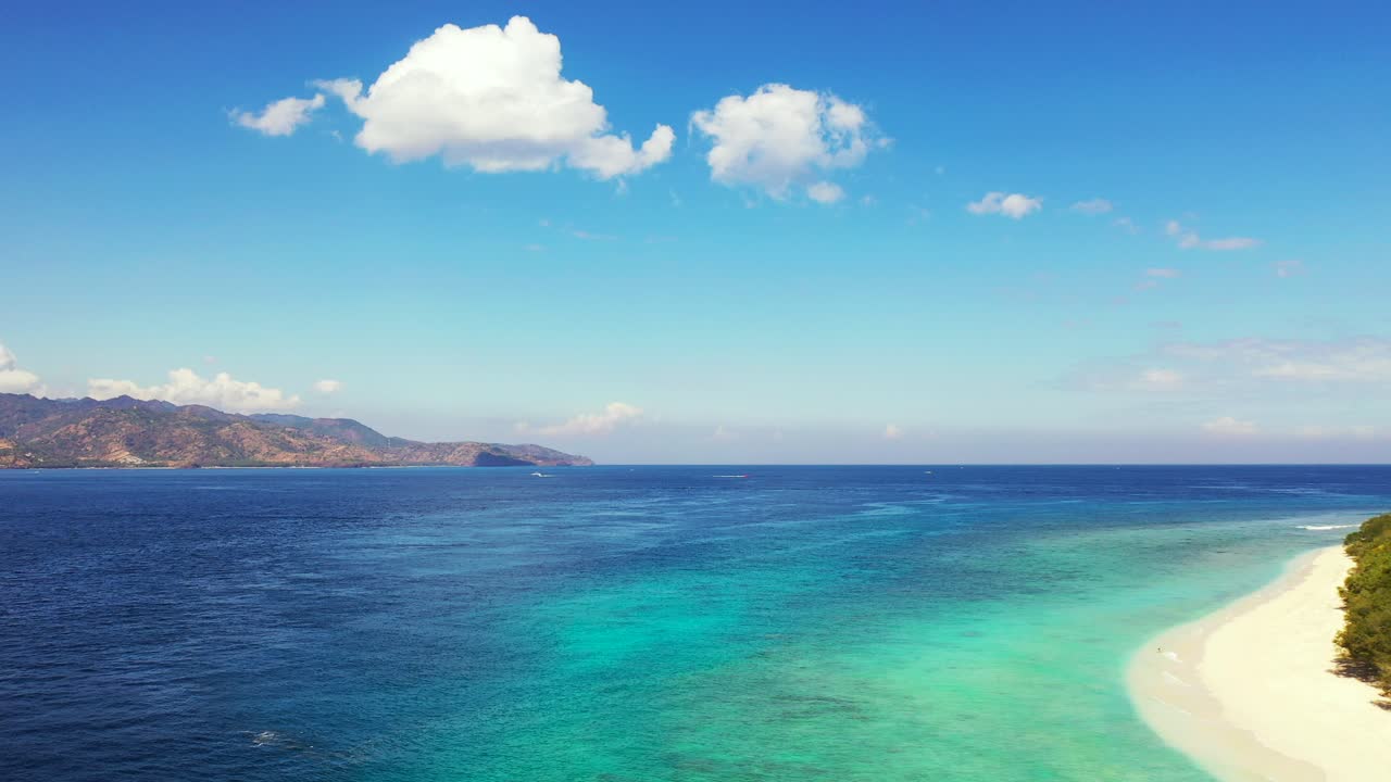 Blue turquoise sea between two beautiful tropical islands under bright sky with overhanging white clouds, vacation postcard from Bali