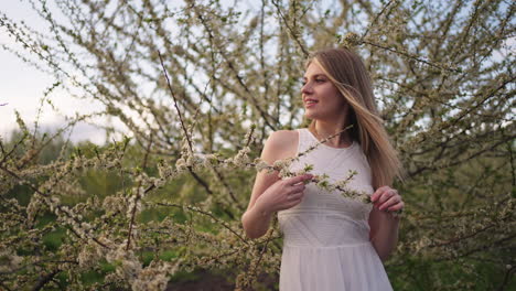 pretty young woman is posing near blooming cherry tree in garden in spring day portrait