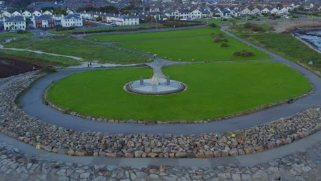 Cinematic-aerial-pullback-featuring-the-Celia-Griffin-Memorial-Park-in-Salthill,-Ireland