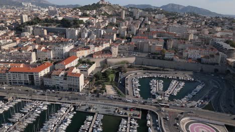 Vista-Aérea-De-Marsella,-Francia,-Paisaje-Urbano,-Tráfico-En-La-Carretera-Costera,-Paseo-Marítimo-Y-Puerto-Deportivo-En-El-Puerto-De-La-Ciudad-Vieja