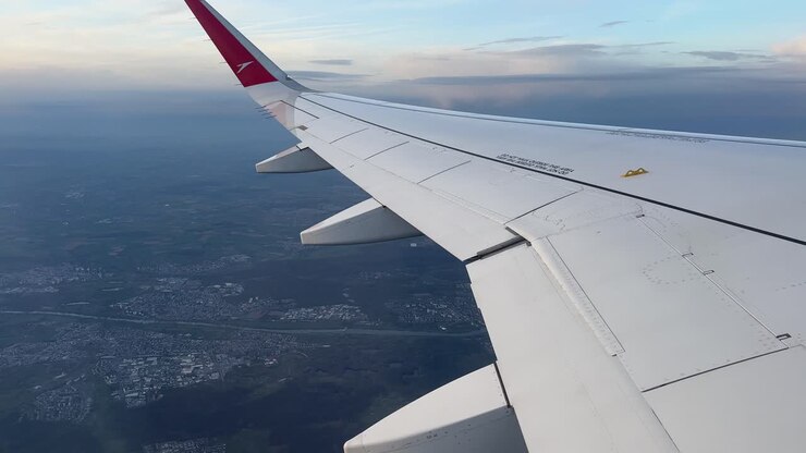 Vista dall'ala dell'aereo durante il volo su Francoforte con il paesaggio urbano sottostante e un orizzonte con cielo serale tenue.