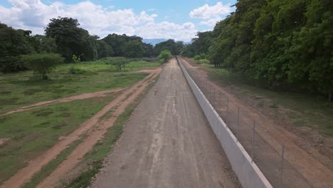 Slow-aerial-forward-flight-along-fence-with-wall-in-rural-area-between-Haiti-and-Dominican-REPUBLIC