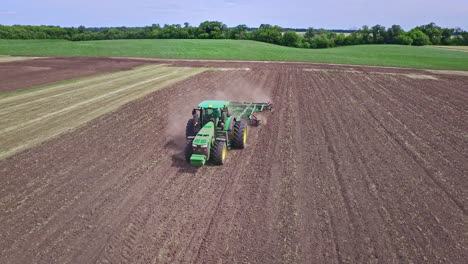 farm tractor with trailer for ploughing working on arable field. farming aerial