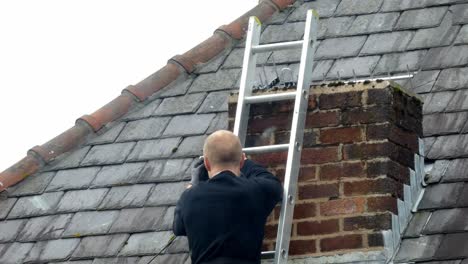 man on ladder installing digital television aerial on home chimney roof