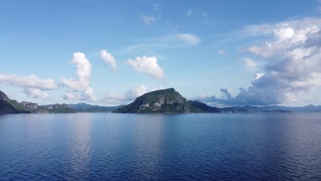 Aerial-View-:Tropical-seascape-horizon-of-multiple-limestone-sea-mount-islands-scattered-in-background-under-interesting-formation-of-large-puffy-white-clouds-and-blue-sky