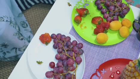 Las-Manos-De-Las-Mujeres-Toman-Sabrosas-Uvas,-Fresas-Y-Duraznos-En-Platos