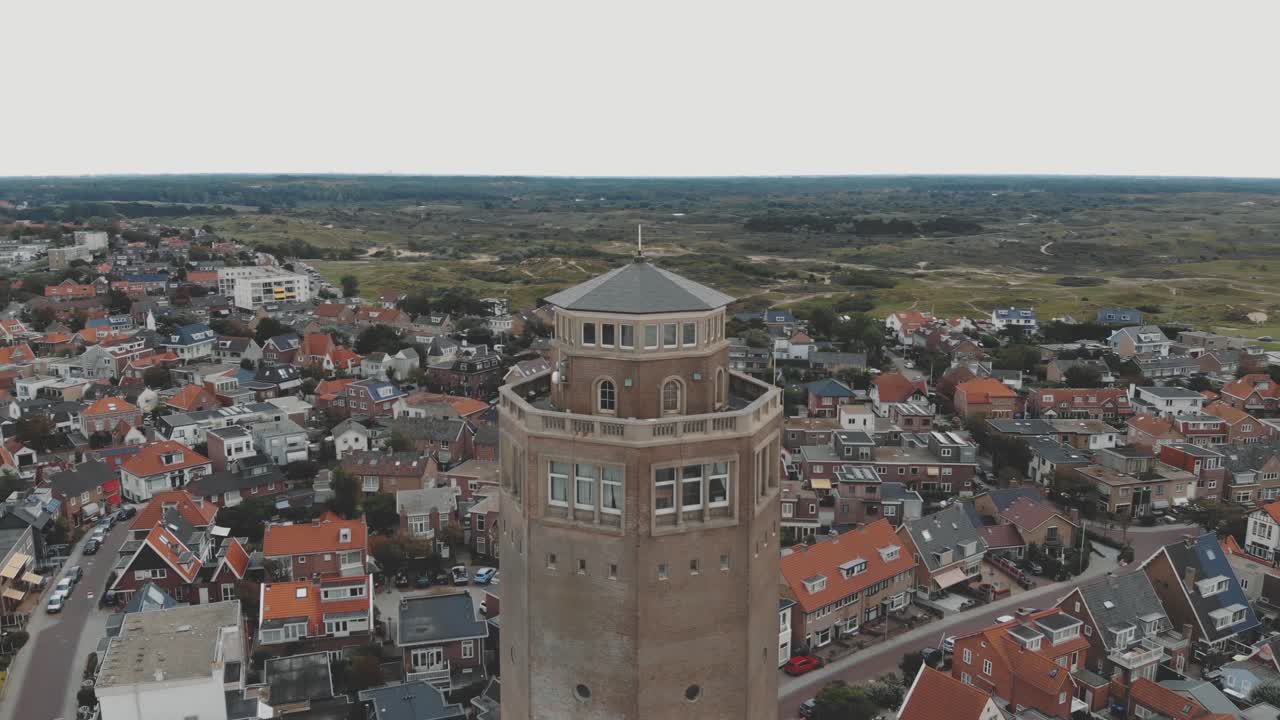 Drone footage circling a water tower and surrounding city of Zandoort, Netherlands