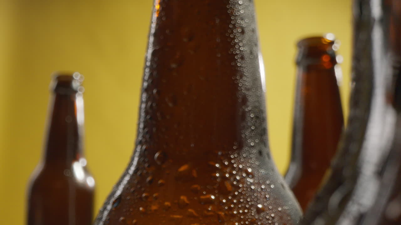 acercamiento de gotas de condensación en botellas de cerveza fría o bebidas gaseosas contra un fondo amarillo