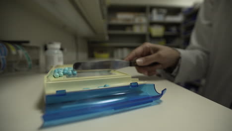 pílulas de medicação sendo medidas pelo farmacêutico em farmácia - câmera lenta - 4k uhd