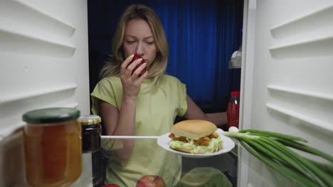 woman eating late night snack from fridge