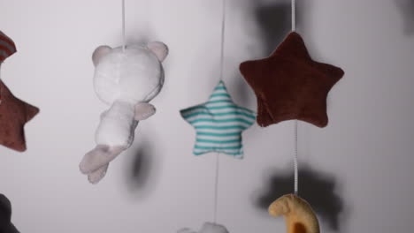 woven toys hanging on crib mobile with lullaby music inside a nursery room